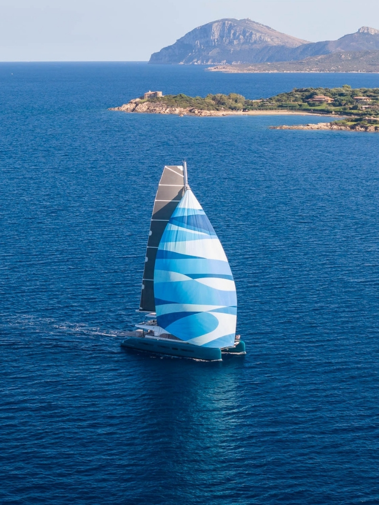 Lagoon Eighty2 sailing with patterned blue and white sail on deep Mediterranean water