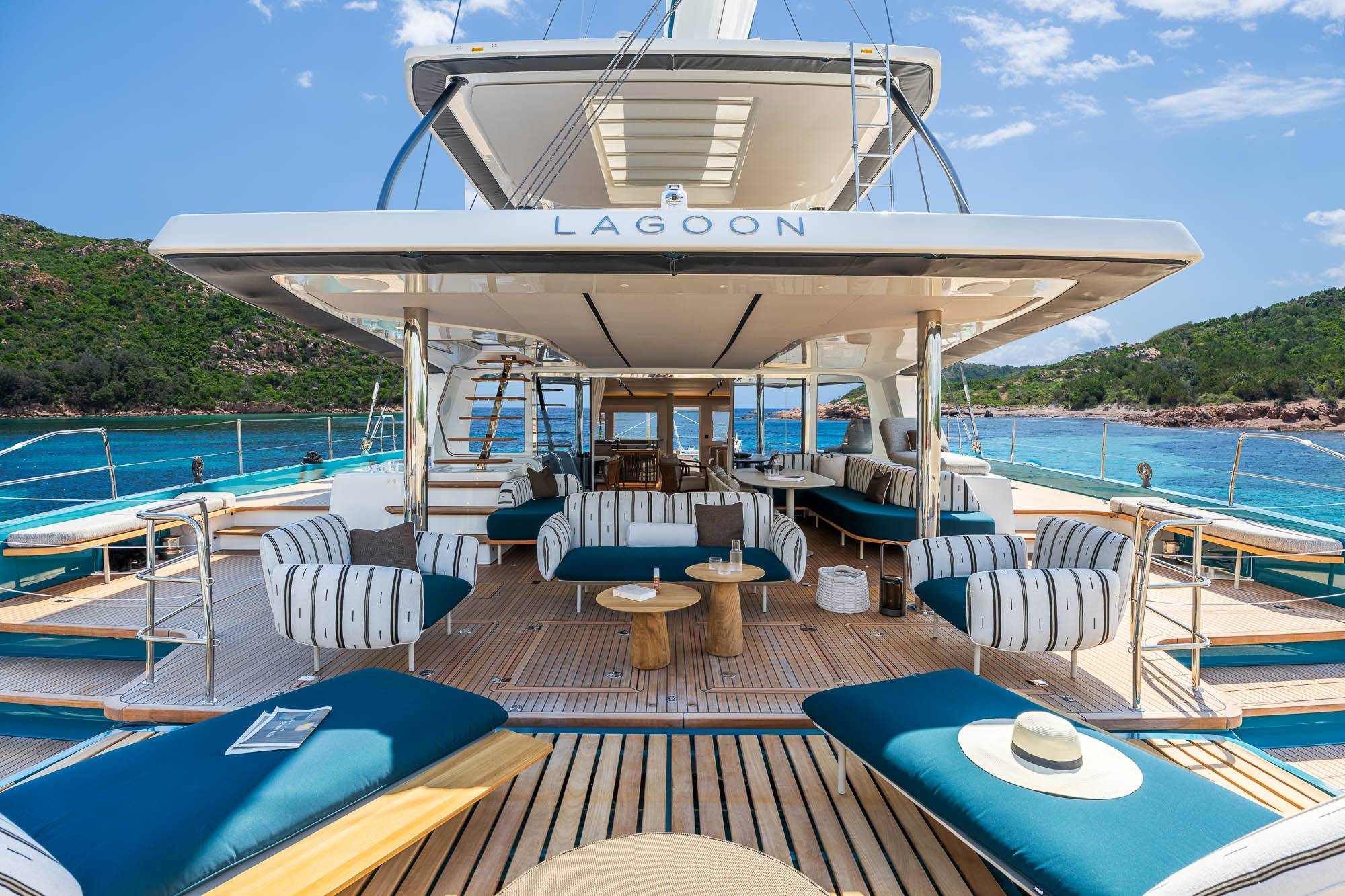 Spacious aft deck lounge of the Lagoon Eighty2 with striped sofas, teak decking and open sea views
